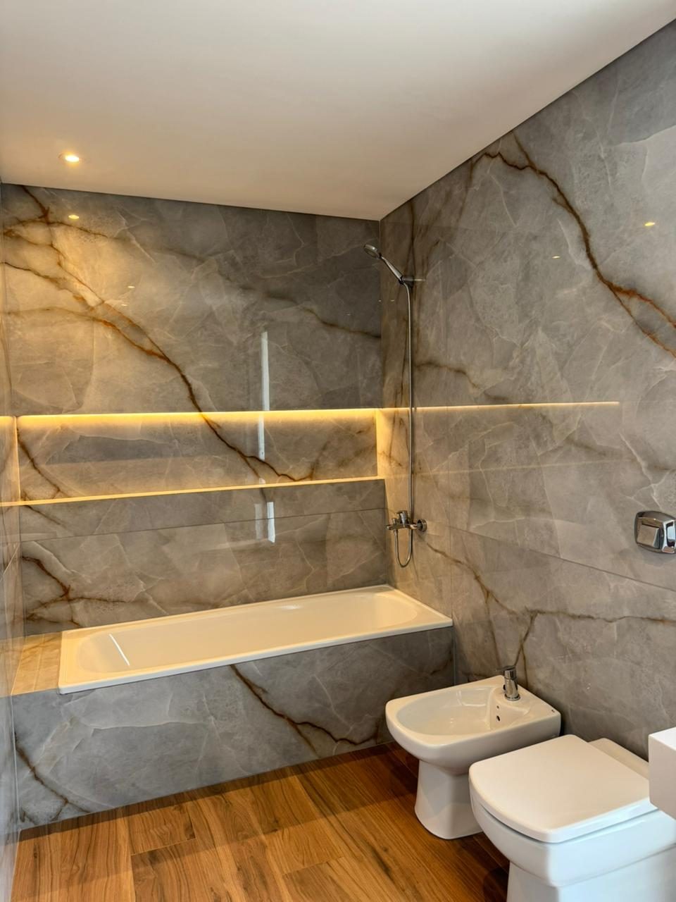 Baño con revestimiento símil mármol y grifería de diseño